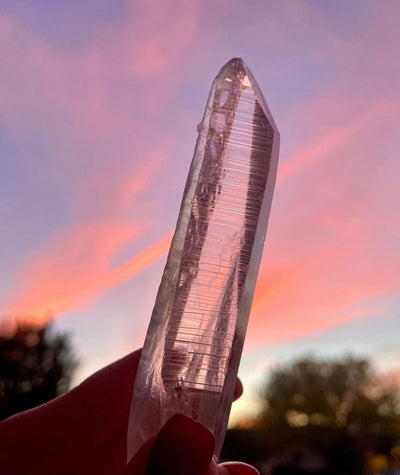raw natural crystals with a beautiful colorful sunset. lemurian clear quartz natural point for crystal healing and manifesting and meditation